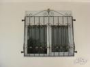 A window, showing the shutters and wrought iron security grilles